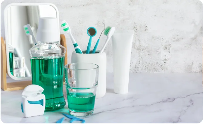 Mouthwash, toothbrushes and dental floss on a bathroom shelf