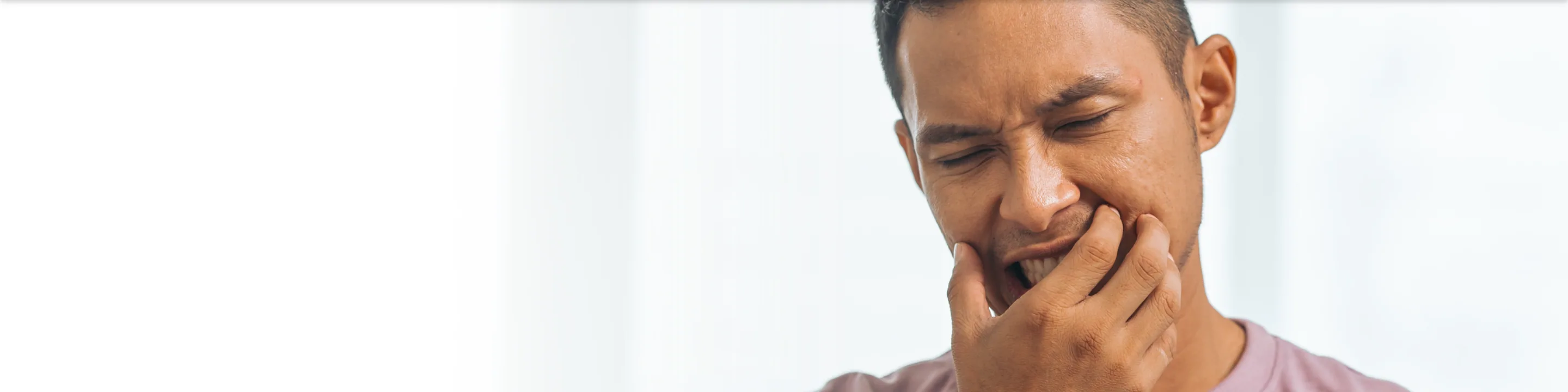 A man holding his jaw in pain from a toothache