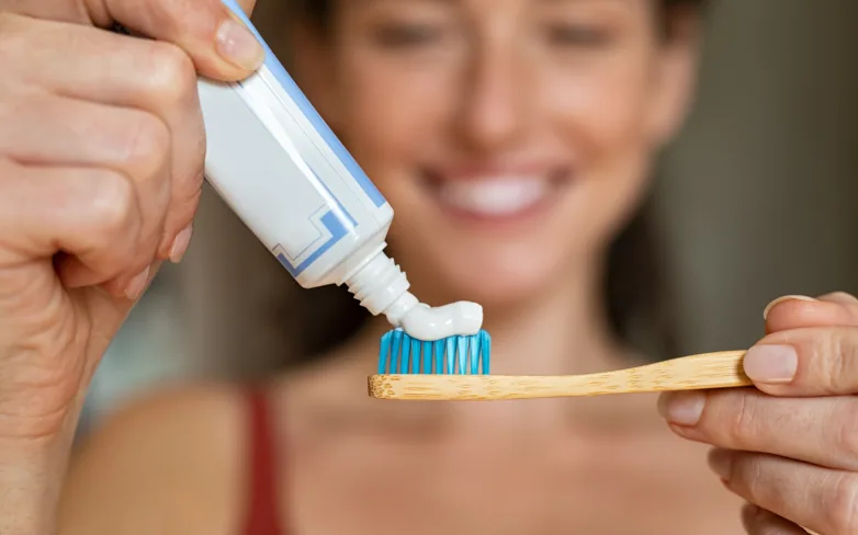 A woman squeezing toothpaste onto a toothbrush