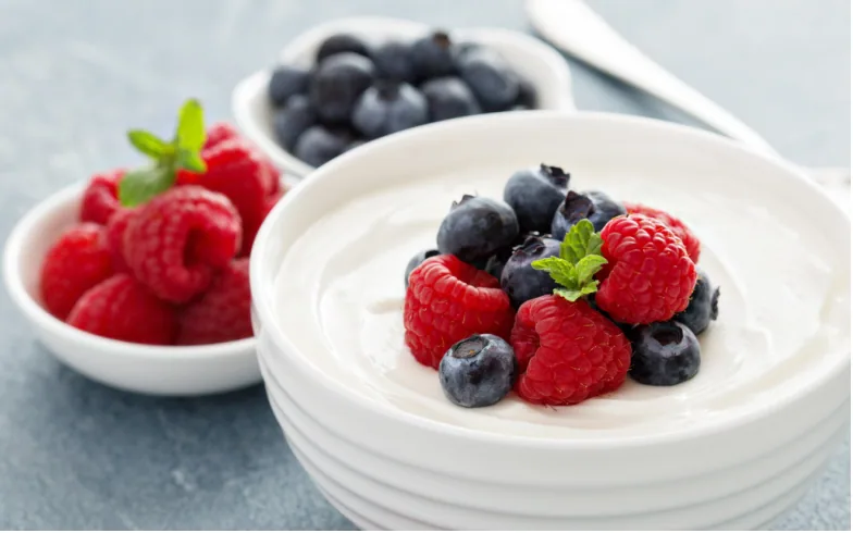 A bowl of yoghurt topped with raspberries and blueberries