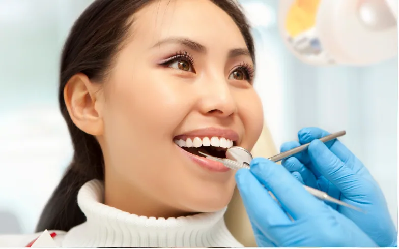 A smiling woman having her teeth checked by a dentist